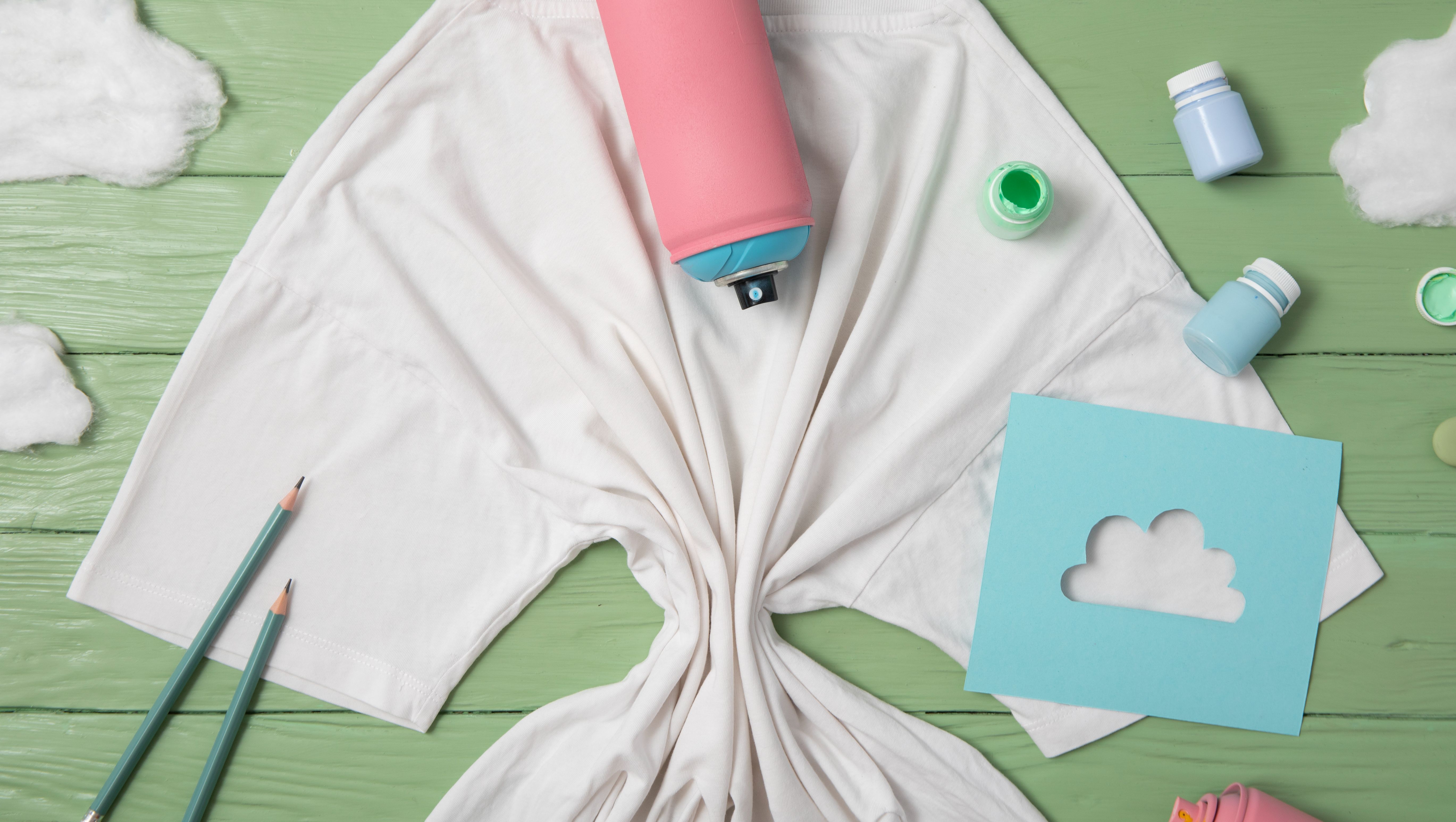 vit t-shirt på grönt bord med sytillbehör